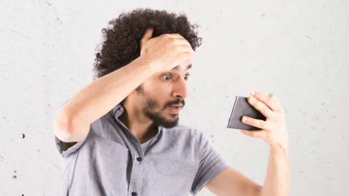 Person holding forehead looking at mobile phone