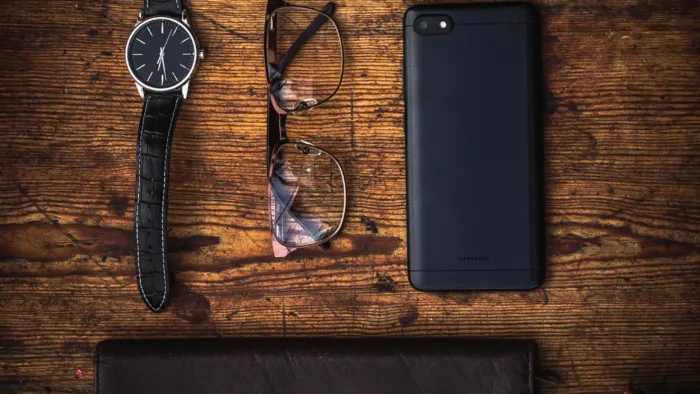black watch, eyeglasses, phone, glasses case and checkbook set out on a table