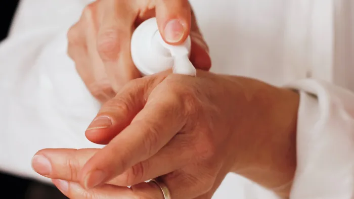 a close up of hands applying lotion