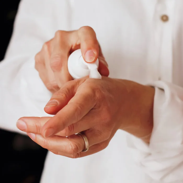 a close up of hands applying lotion